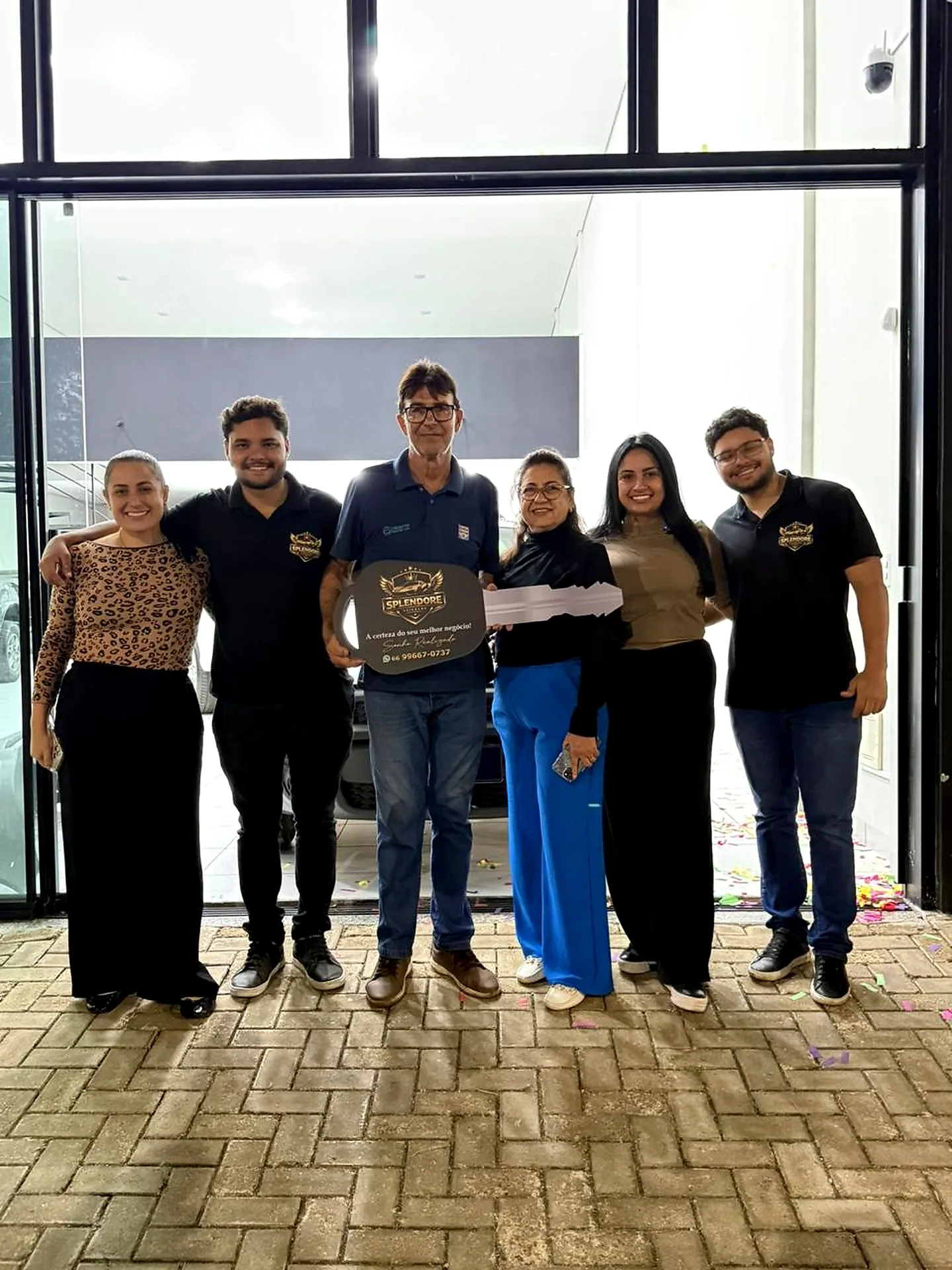 Equipe e clientes comemorando a entrega do veículo